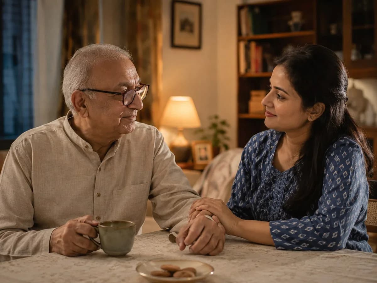 Adult daughter gently holding her elderly father's hand across a table at home